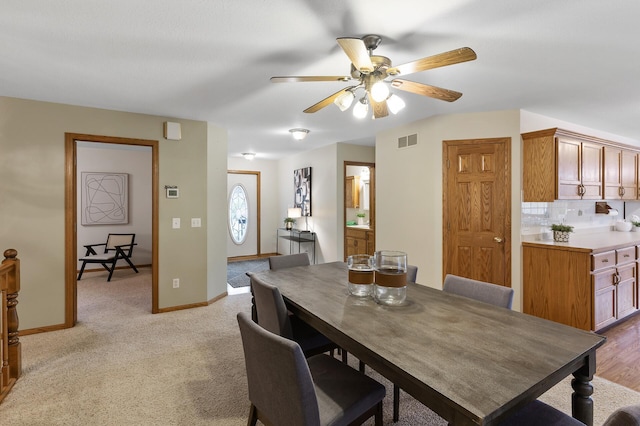 carpeted dining room with ceiling fan