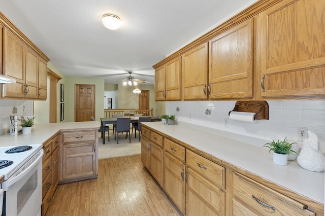 kitchen featuring light hardwood / wood-style floors, kitchen peninsula, tasteful backsplash, ceiling fan, and electric stove