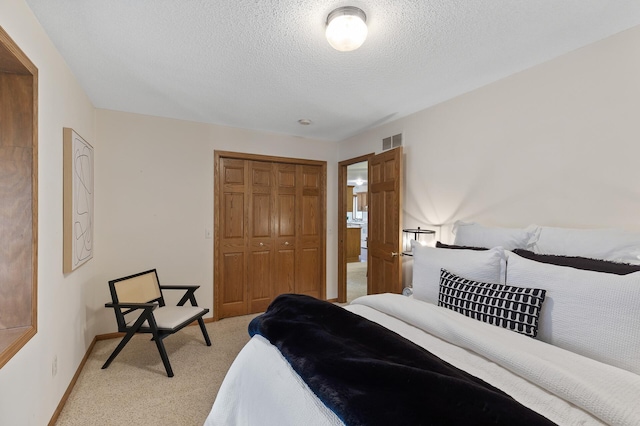 bedroom with light colored carpet, a textured ceiling, and a closet