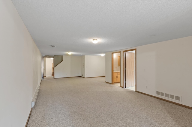 basement featuring a textured ceiling and light colored carpet