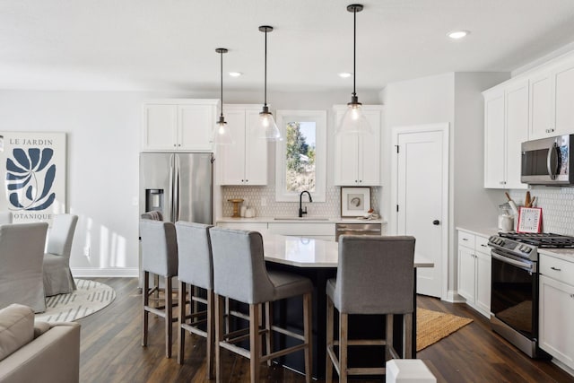 kitchen featuring a center island, white cabinets, pendant lighting, and appliances with stainless steel finishes