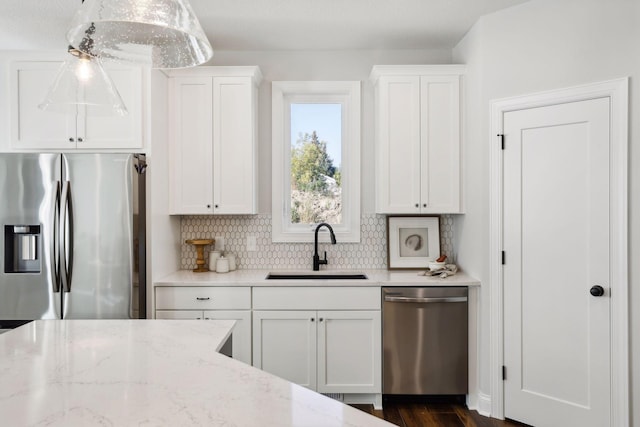 kitchen with sink, decorative light fixtures, light stone counters, white cabinetry, and stainless steel appliances