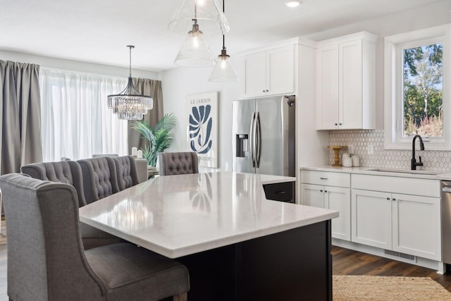 kitchen featuring white cabinets, sink, hanging light fixtures, appliances with stainless steel finishes, and a kitchen island