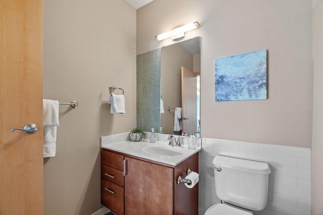 bathroom with vanity, tile walls, and toilet