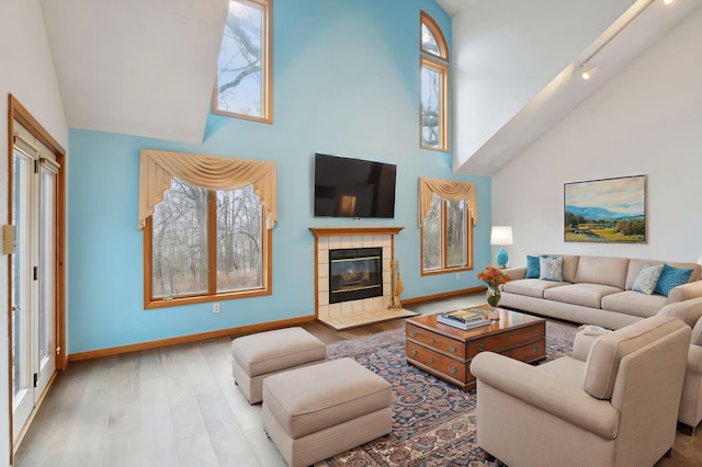 living room featuring a fireplace, high vaulted ceiling, and light hardwood / wood-style flooring