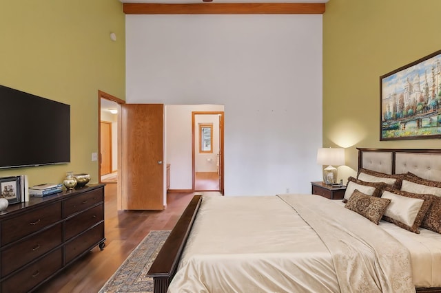 bedroom with connected bathroom, high vaulted ceiling, and dark wood-type flooring