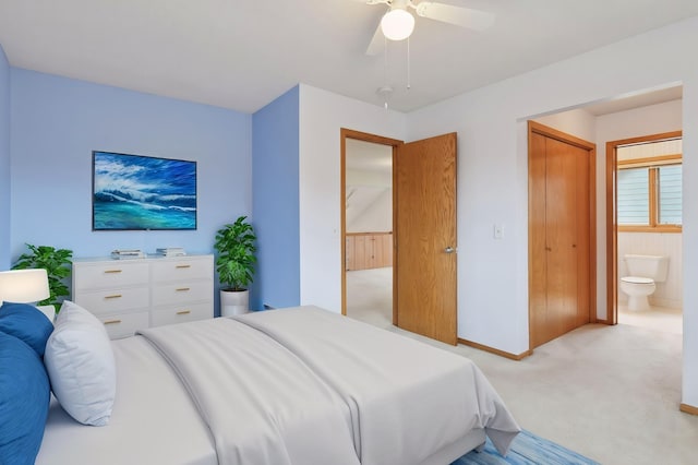 bedroom featuring a closet, light colored carpet, ensuite bath, and ceiling fan