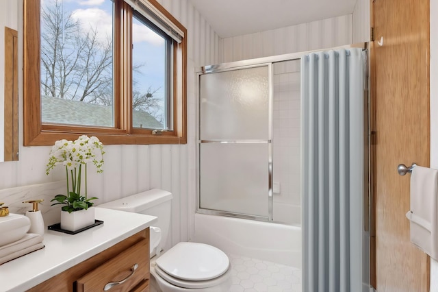 full bathroom with vanity, a healthy amount of sunlight, toilet, and shower / bath combination with glass door