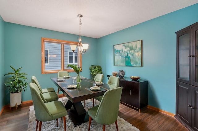 dining space with dark wood-type flooring, baseboards, and an inviting chandelier