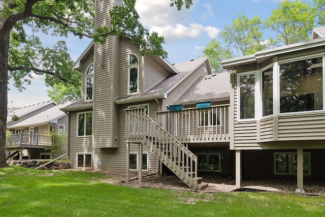 rear view of house featuring a chimney, a yard, a deck, and stairs