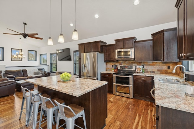kitchen with wood finished floors, lofted ceiling, dark brown cabinets, open floor plan, and stainless steel appliances