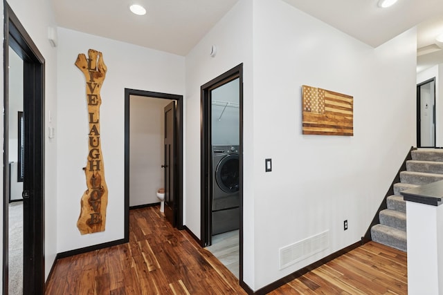 hallway featuring visible vents, washer / clothes dryer, wood finished floors, and stairway