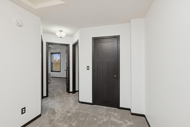 corridor featuring baseboards and light colored carpet