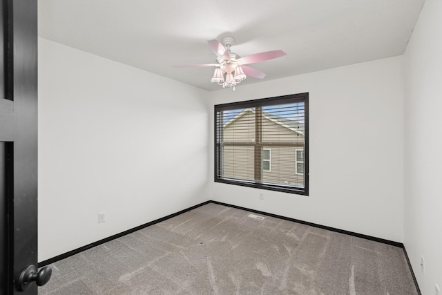 spare room with carpet floors, a ceiling fan, and baseboards