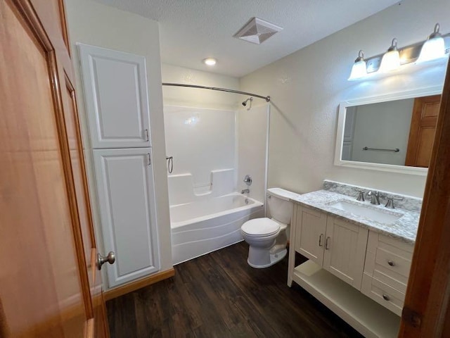 full bathroom with toilet, shower / bath combination, wood-type flooring, vanity, and a textured ceiling