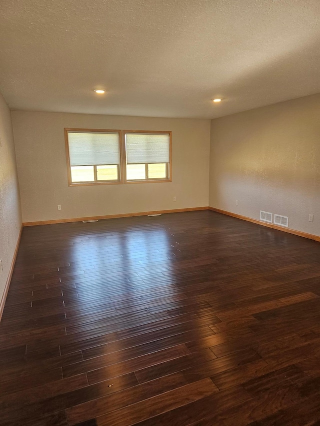 unfurnished room with a textured ceiling and dark wood-type flooring