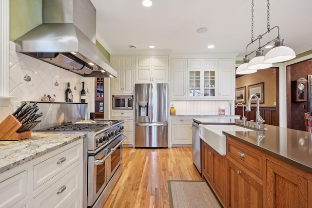 kitchen with appliances with stainless steel finishes, hanging light fixtures, tasteful backsplash, island range hood, and white cabinets