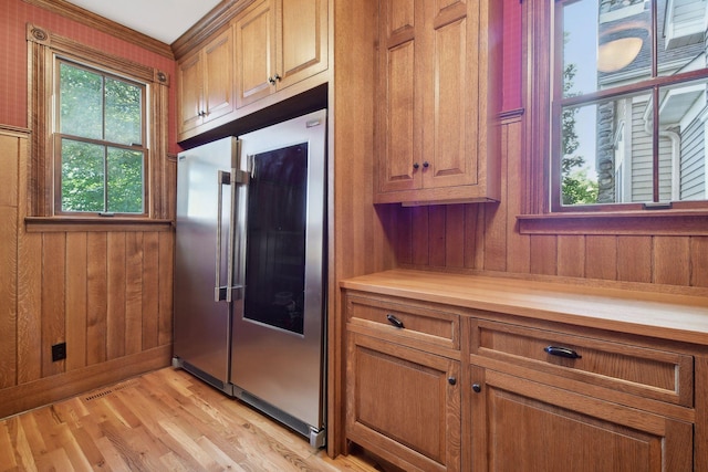 kitchen featuring high quality fridge, wooden walls, butcher block counters, and light hardwood / wood-style floors