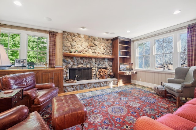 living room with hardwood / wood-style floors, crown molding, a fireplace, and plenty of natural light