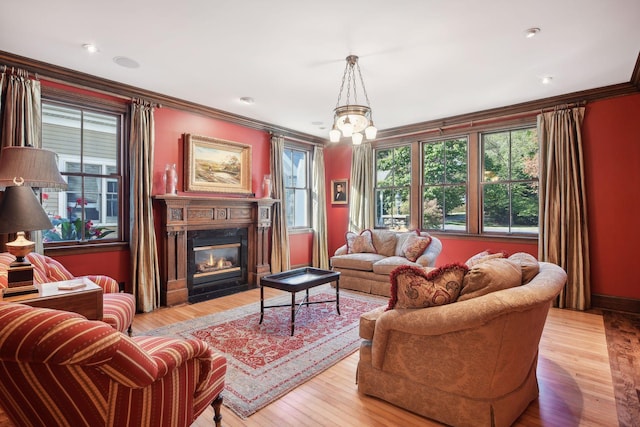 living room featuring a notable chandelier, ornamental molding, and light hardwood / wood-style floors