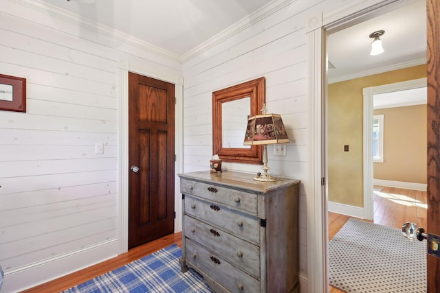 interior space featuring ornamental molding, wooden walls, and light hardwood / wood-style floors