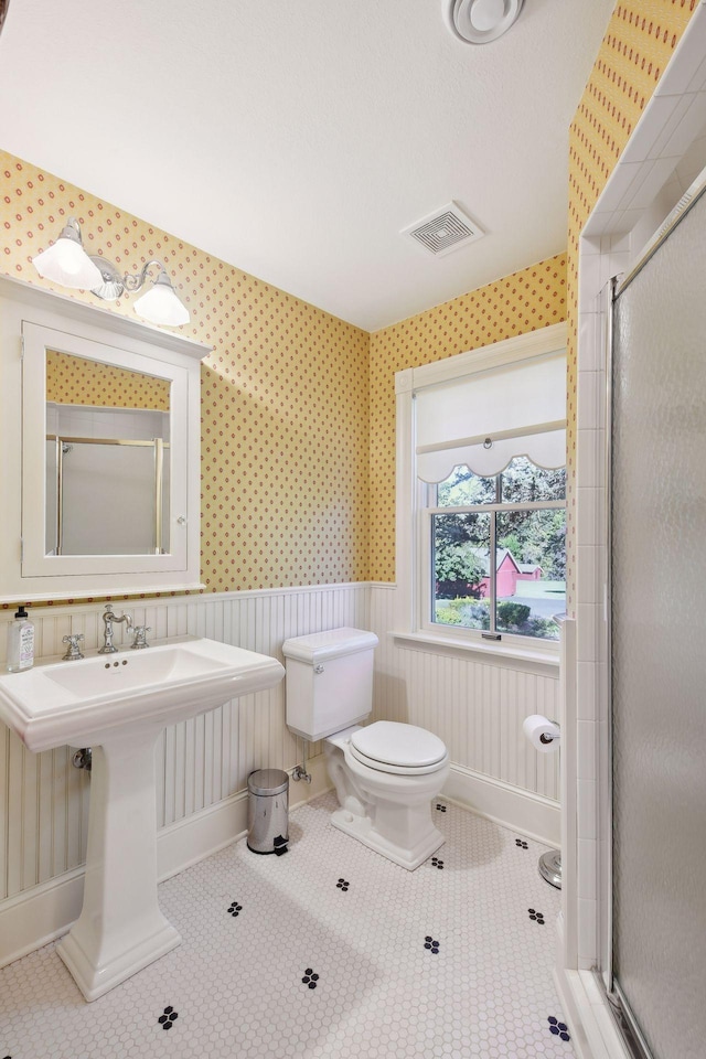 bathroom with toilet, tile patterned floors, and walk in shower