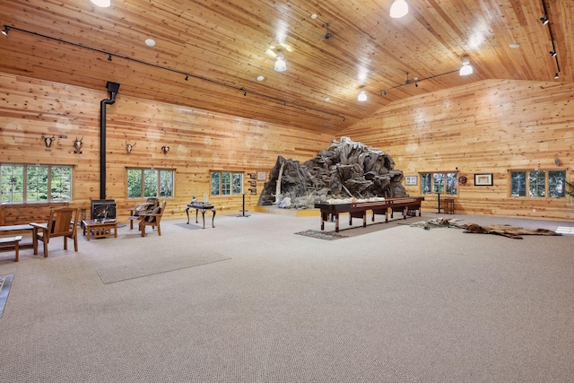 interior space featuring rail lighting, high vaulted ceiling, a wood stove, and wood ceiling