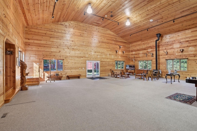 unfurnished room featuring track lighting, high vaulted ceiling, a wood stove, and wooden ceiling