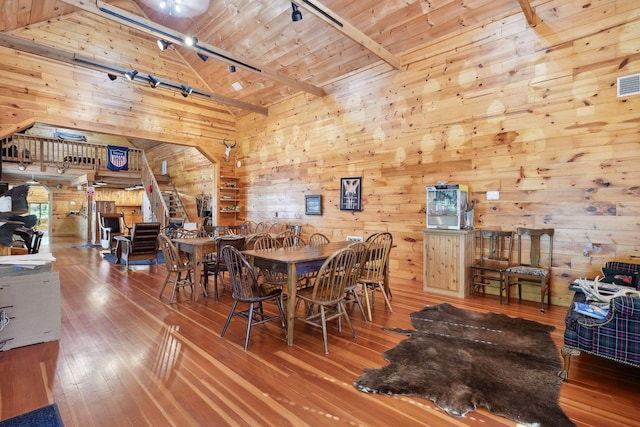 dining area with rail lighting, wood walls, wood ceiling, hardwood / wood-style flooring, and beamed ceiling