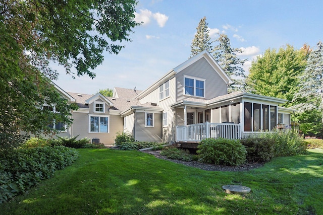 back of house featuring a lawn and a sunroom