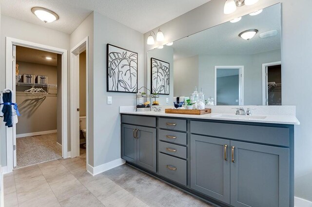 bathroom with a textured ceiling, vanity, and toilet