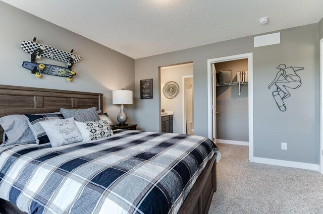 carpeted bedroom featuring a textured ceiling, a closet, and a walk in closet