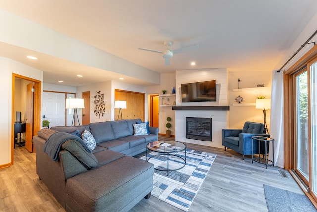 living room featuring a fireplace, vaulted ceiling, ceiling fan, and light hardwood / wood-style flooring