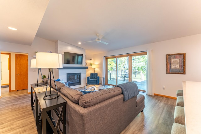 living room featuring ceiling fan, lofted ceiling, and light wood-type flooring