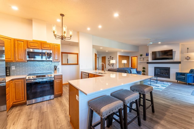 kitchen featuring hanging light fixtures, sink, a kitchen island with sink, stainless steel appliances, and a breakfast bar area