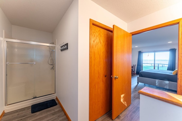 bathroom featuring walk in shower, wood-type flooring, and a textured ceiling