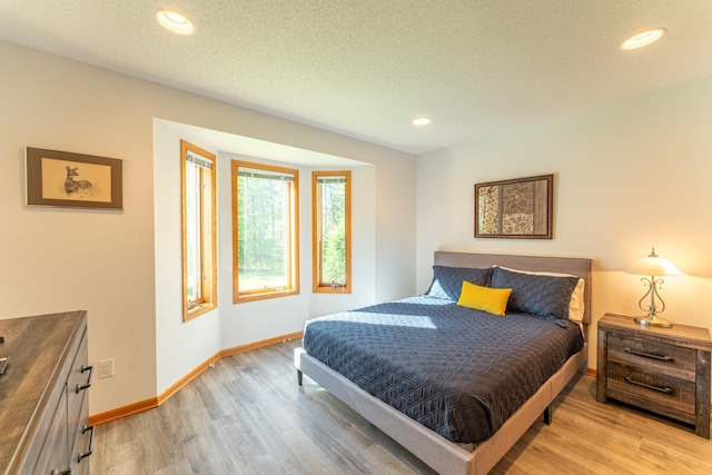 bedroom with light wood-type flooring and a textured ceiling