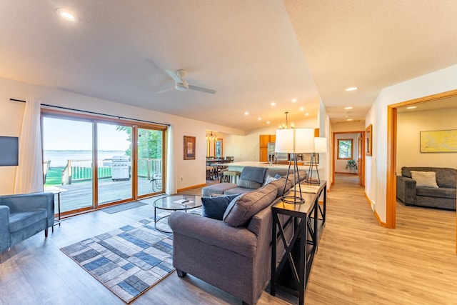 living room with ceiling fan, light hardwood / wood-style floors, and a water view