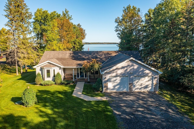 view of front of home featuring a front yard, a garage, a porch, and a water view