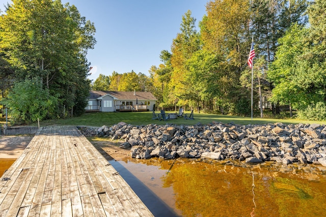 view of dock featuring a yard and a deck with water view