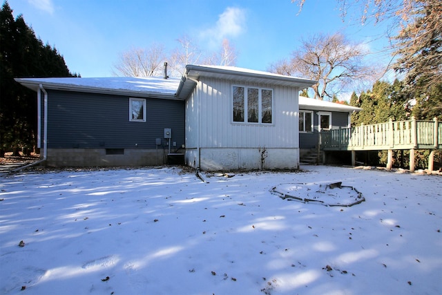 snow covered house featuring a wooden deck