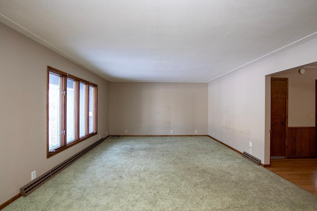 empty room with light colored carpet and a baseboard radiator