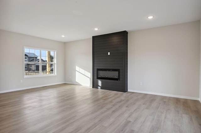 unfurnished living room with a large fireplace and light hardwood / wood-style floors