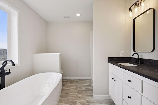 bathroom with vanity, a tub, and a healthy amount of sunlight