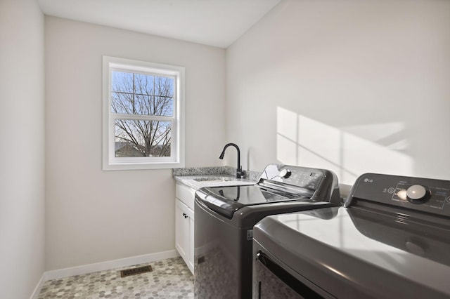 clothes washing area featuring sink, washer and dryer, light tile patterned floors, and cabinets