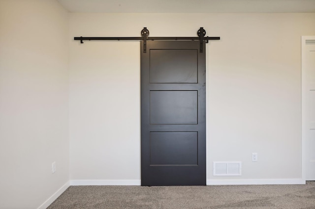 carpeted empty room featuring a barn door