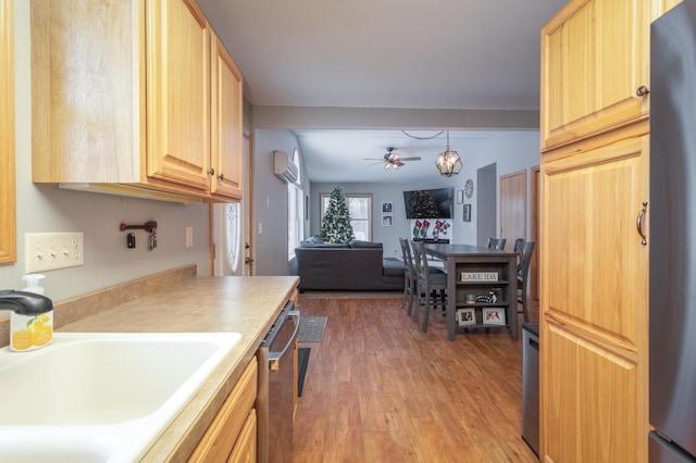 kitchen featuring sink, a wall mounted AC, light brown cabinets, pendant lighting, and stainless steel appliances