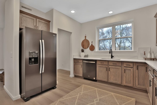 kitchen with light wood-type flooring, stainless steel appliances, and sink