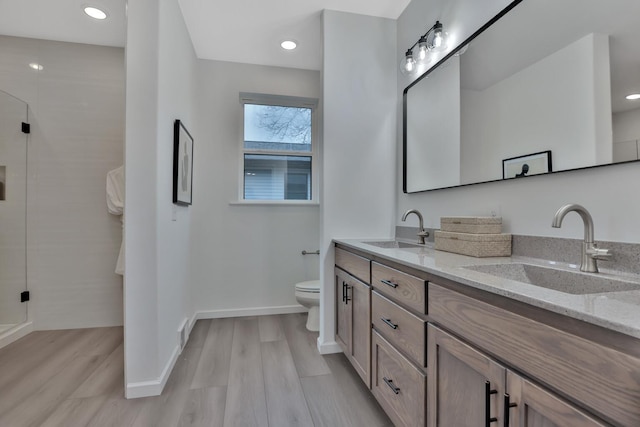 bathroom featuring hardwood / wood-style floors, vanity, a shower with door, and toilet