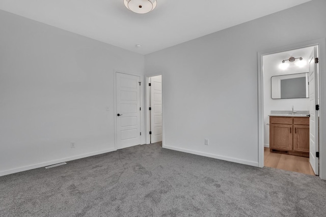 unfurnished bedroom featuring ensuite bath, light carpet, and sink